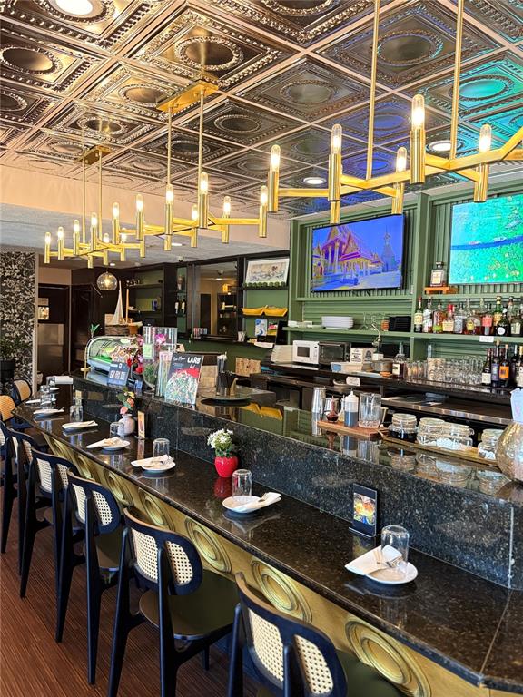 A restaurant bar features black granite countertops, cane-back chairs, and a metallic patterned ceiling — 7900 4TH ST N STREET, ST PETERSBURG, FL