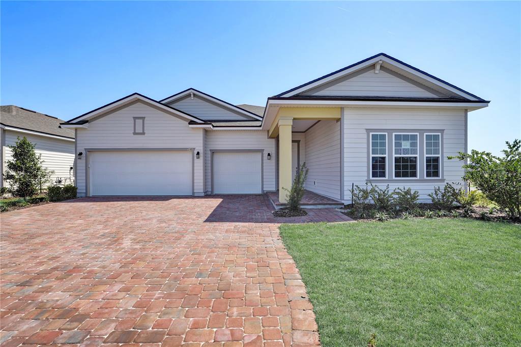 A single-story house with a brick paver driveway, three-car garage, and a covered front porch — 106 BRICKSTONE TRACE, ST AUGUSTINE, FL