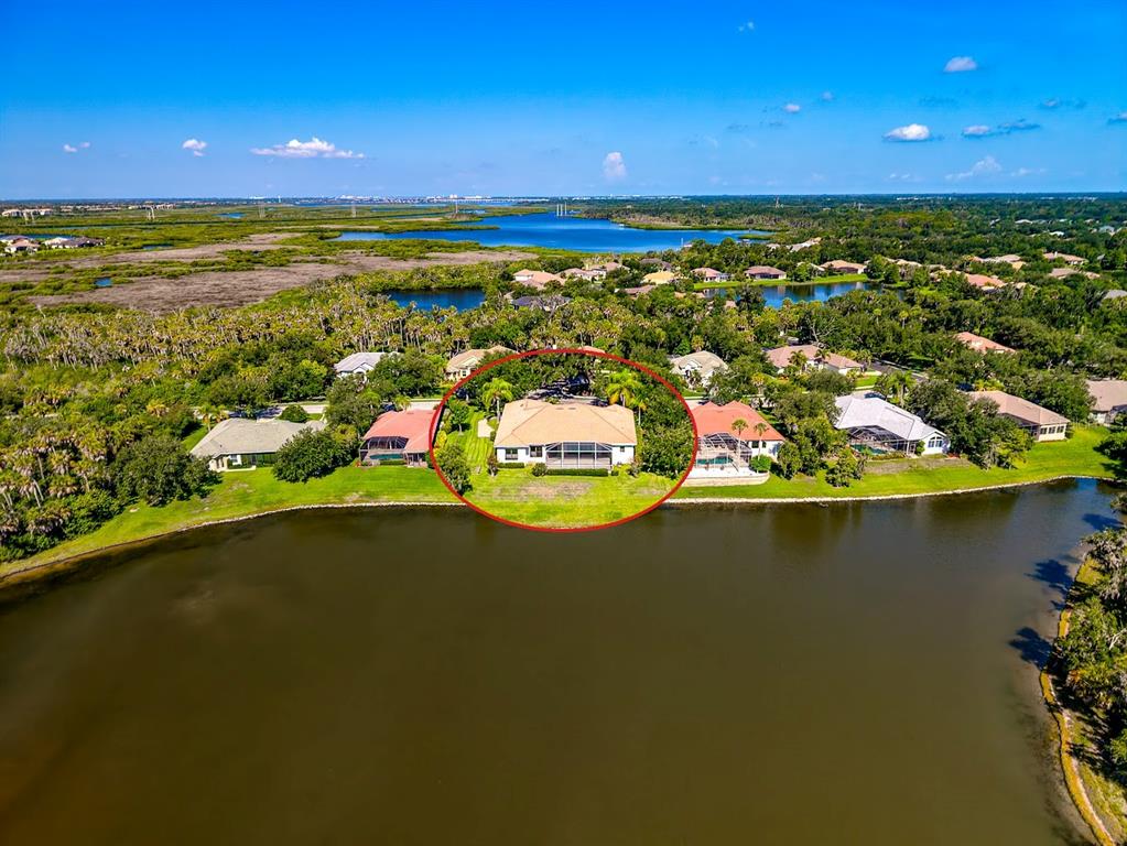 An aerial view shows a single-story house with a screened pool enclosure overlooking a lake — 2012 ISLAND ESTATES DRIVE, PARRISH, FL