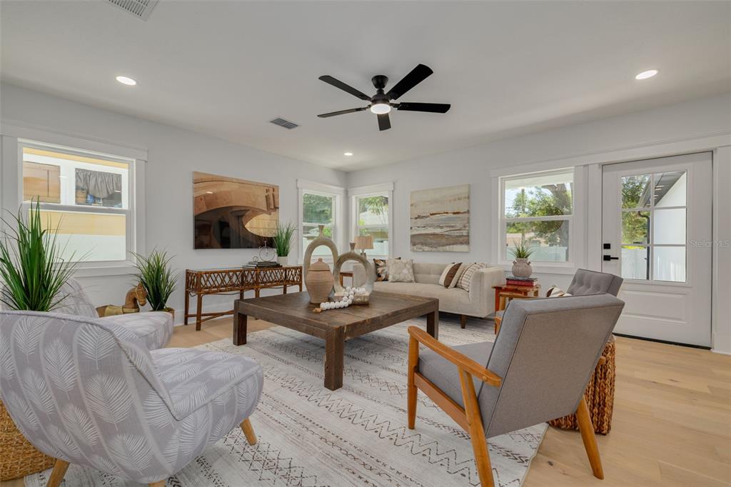 A bright living room features light wood floors, a ceiling fan, and neutral furniture — 1426 15TH STREET N, ST PETERSBURG, FL