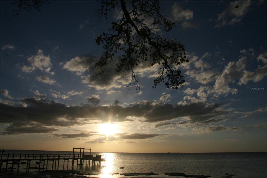 A wooden pier extends into a calm body of water during a sunset with clouds — 000 BLUFF BOULEVARD, HOLIDAY, FL