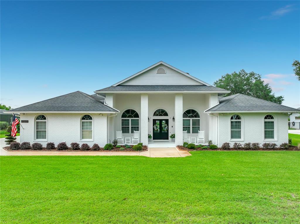 A white brick house with a covered front porch and arched windows under a blue sky — 34449 PARKVIEW AVENUE, EUSTIS, FL