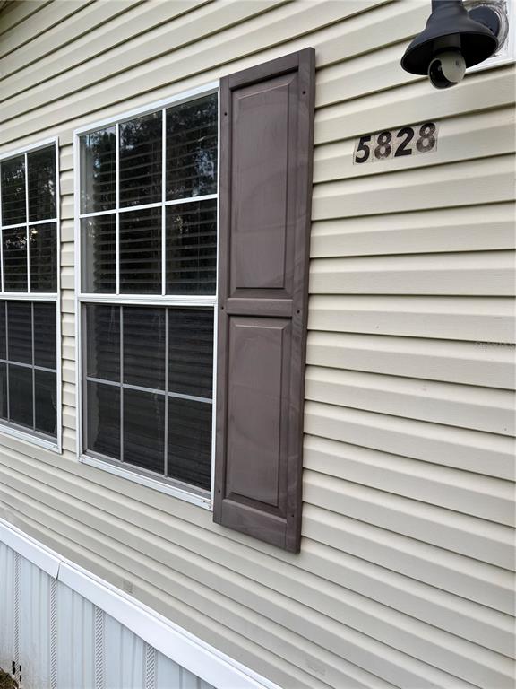 The exterior of a house features beige vinyl siding, a window with shutters, and a light — 5828 BRYCE STREET, KEYSTONE HEIGHTS, FL