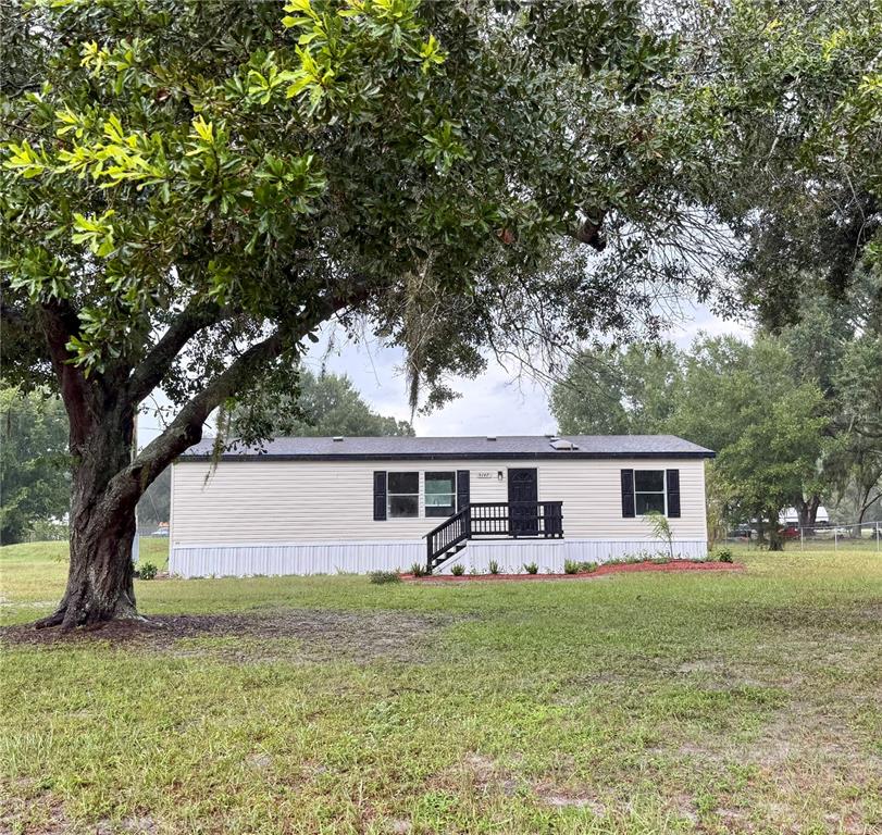A single-story manufactured home with light siding, black shutters, and a small front porch — 5147 ROCK DOVE LOOP, LAKELAND, FL