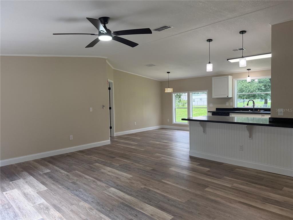 An open-concept living and kitchen area features wood-look flooring, a ceiling fan, and pendant lighting — 5147 ROCK DOVE LOOP, LAKELAND, FL