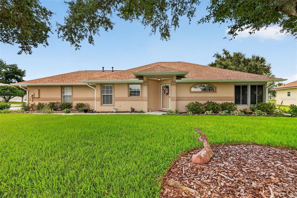 A tan, single-story ranch-style house with a brown shingled roof and a front lawn — 5704 KING JAMES AVENUE, LEESBURG, FL
