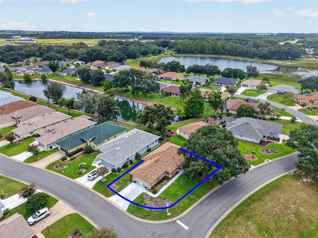 An aerial view shows a single-story house with a brown roof on a corner lot — 5704 KING JAMES AVENUE, LEESBURG, FL