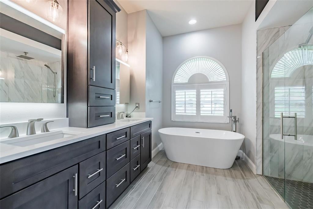 A modern bathroom features a dark wood vanity, a freestanding tub, and a glass shower — 10131 PADDOCK OAKS DRIVE, RIVERVIEW, FL