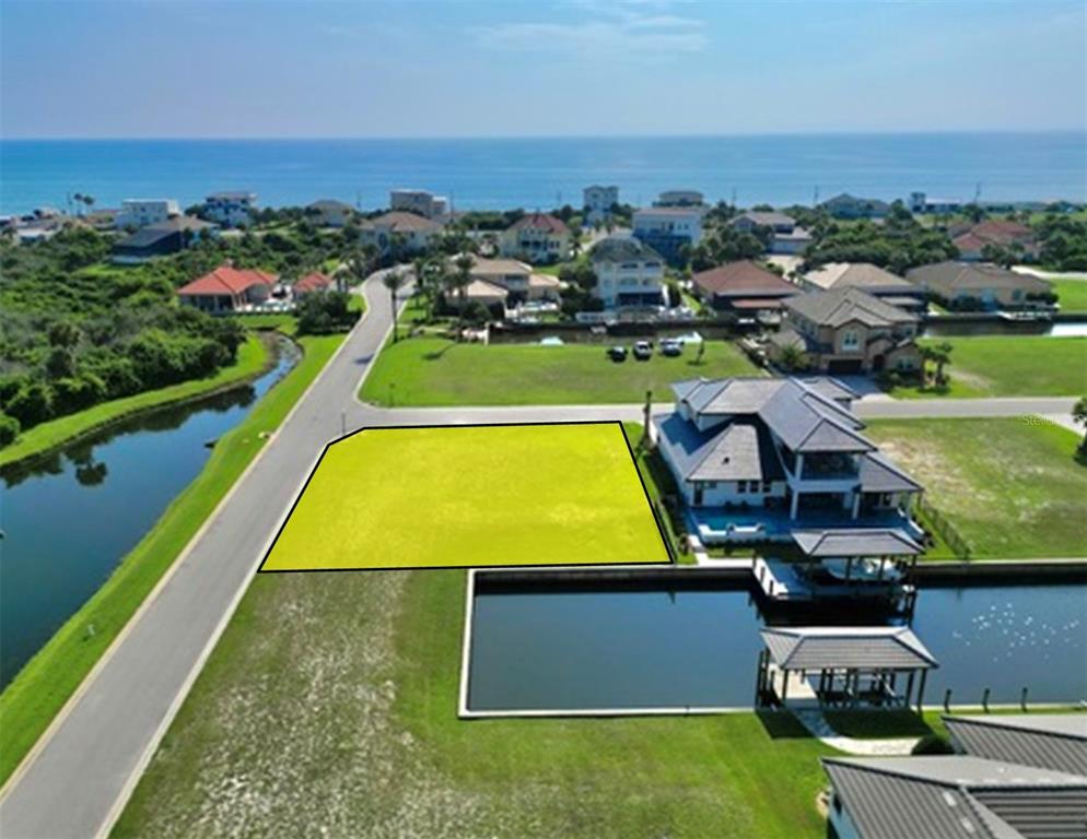 An aerial view shows a vacant, highlighted residential lot situated next to a canal — 61 MALIBU COVE, FLAGLER BEACH, FL
