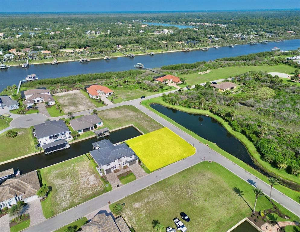 An aerial view shows a vacant, yellow-highlighted residential lot situated next to a canal — 61 MALIBU COVE, FLAGLER BEACH, FL