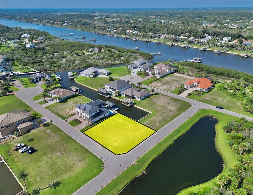 An aerial view shows a vacant, yellow-highlighted residential lot situated between a canal and a road — 61 MALIBU COVE, FLAGLER BEACH, FL