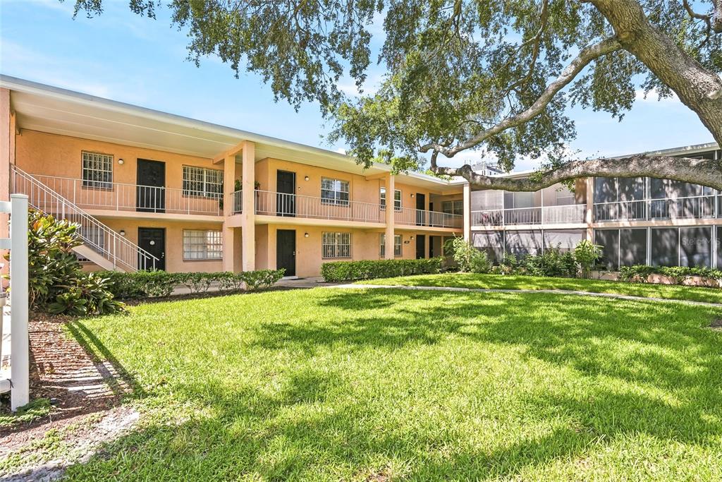 A two-story apartment building with exterior walkways, stairs, and a grassy courtyard — 4702 MICHAEL COURT UNIT 142, TAMPA, FL