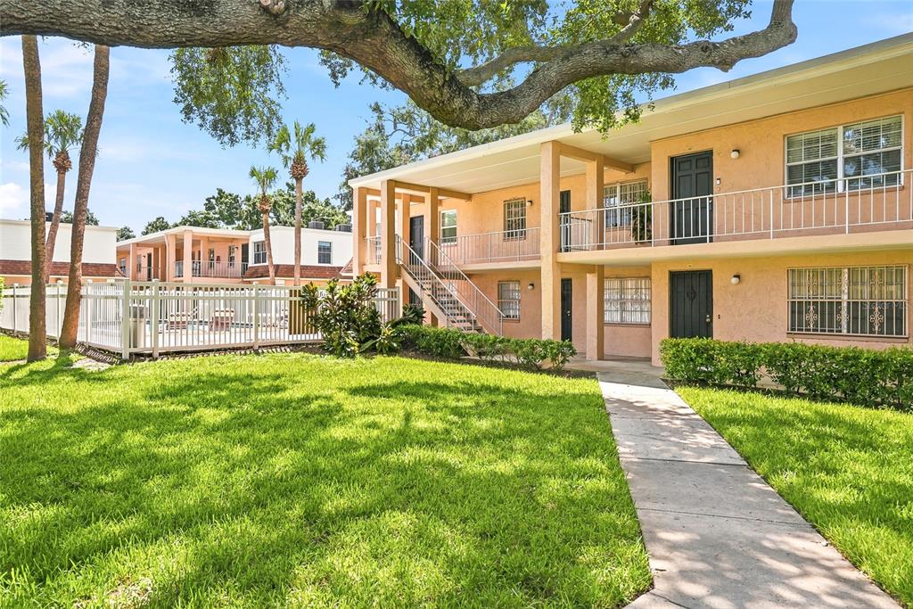 A two-story apartment building with a walkway, lawn, and a fenced pool area — 4702 MICHAEL COURT UNIT 142, TAMPA, FL