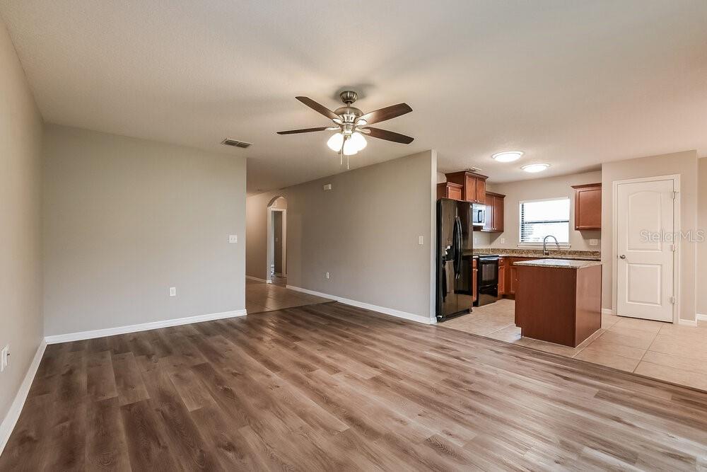 An open-concept living area with wood-look flooring leads into a kitchen with dark wood cabinets — 4292 ABACO DRIVE, TAVARES, FL