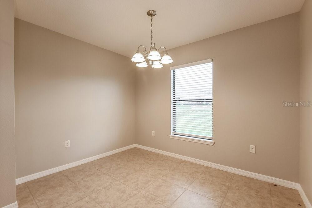An empty dining room features beige walls, tile flooring, a chandelier, and a single window — 4292 ABACO DRIVE, TAVARES, FL