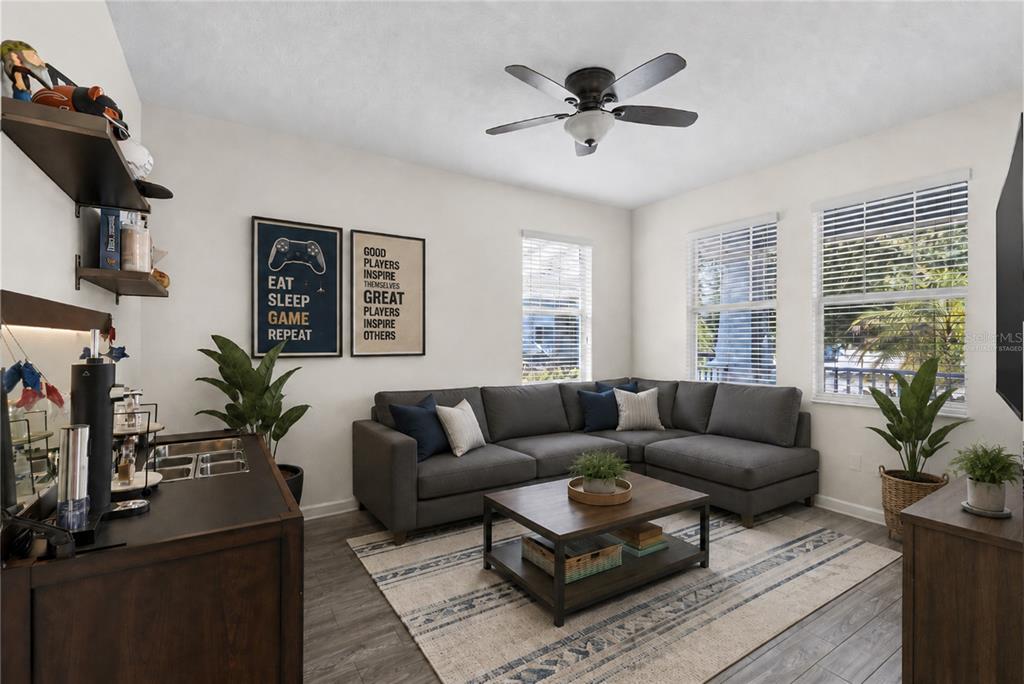 A room with wood-look flooring, a gray sofa, a ceiling fan, and a wet bar — 12016 FICTION AVENUE, ORLANDO, FL