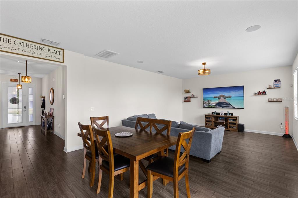 A living room features dark wood-look flooring, a television, a bar cabinet, and a ceiling fan — 12016 FICTION AVENUE, ORLANDO, FL