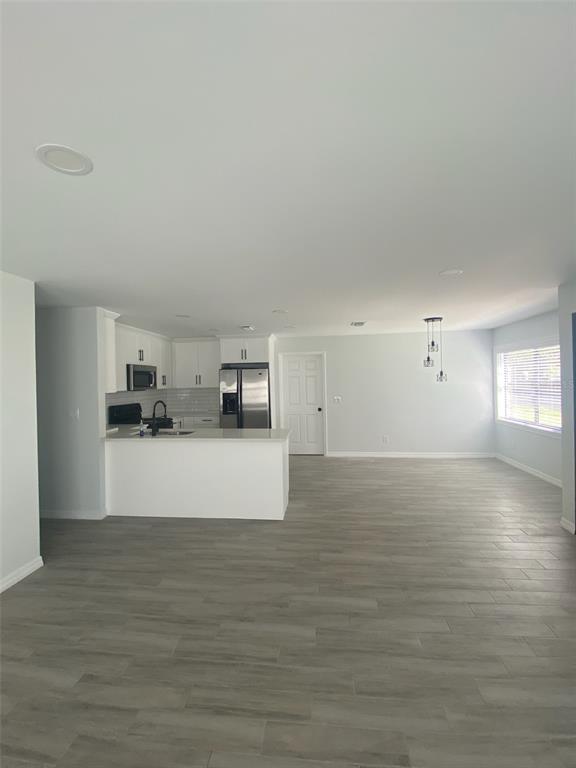 An open-concept kitchen and living area features white cabinetry, stainless steel appliances, and gray flooring — 5008 PARADE STREET, TAMPA, FL