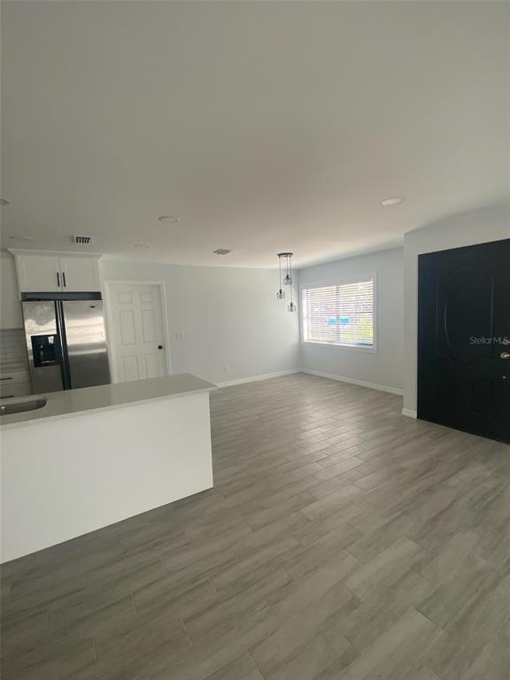 A kitchen with a breakfast bar, stainless steel refrigerator, and light gray wood-look tile flooring — 5008 PARADE STREET, TAMPA, FL