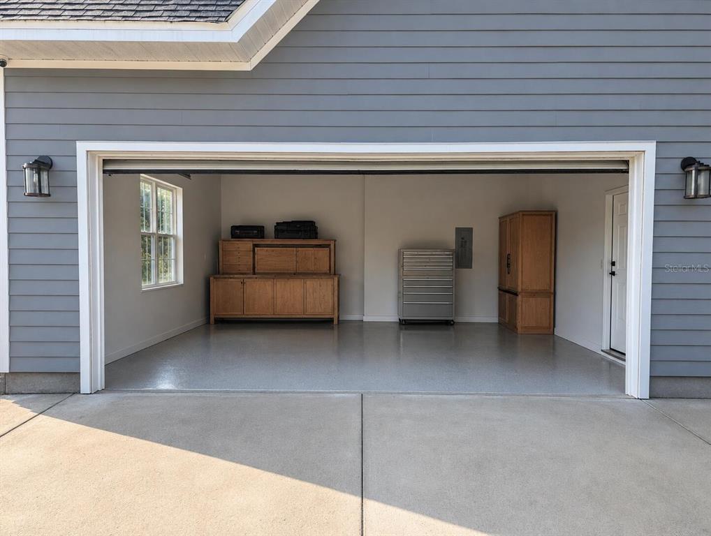 A two-car garage with gray siding, a concrete floor, and wooden storage cabinets — 841 NW 4TH AVENUE, WILLISTON, FL