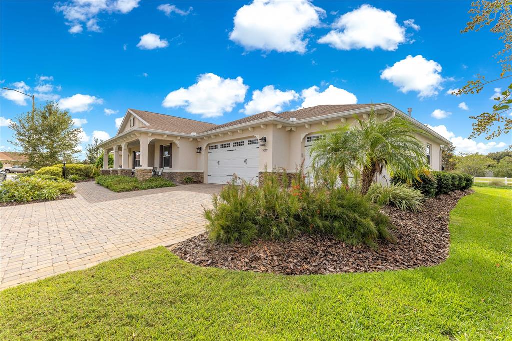 A single-story house with a beige stucco exterior, a paver driveway, and a two-car garage — 9099 SW 89TH LOOP, OCALA, FL