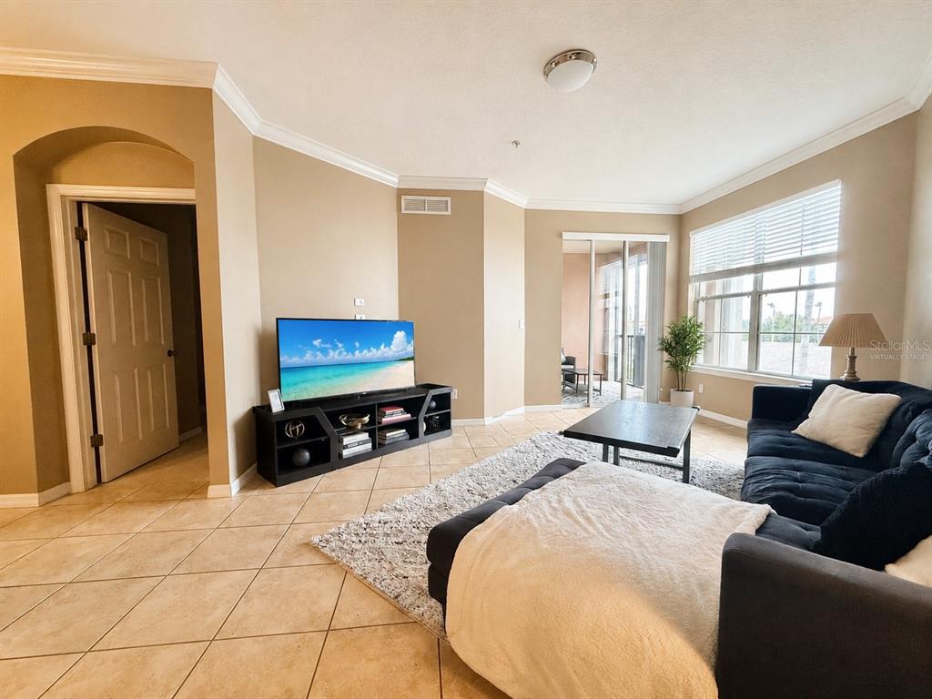 A living room features beige walls, tile flooring, a dark media console, and a sofa — 8168 BOAT HOOK LOOP UNIT 724, WINDERMERE, FL