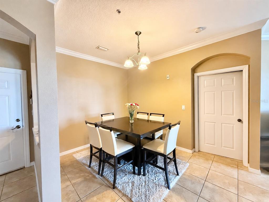 A dining room features a dark wood table, four white chairs, and a chandelier — 8168 BOAT HOOK LOOP UNIT 724, WINDERMERE, FL