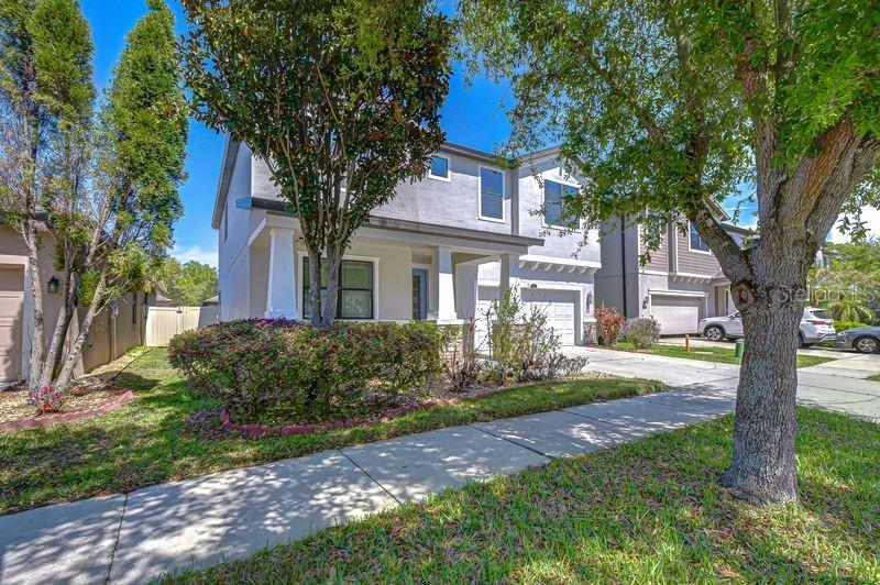 A two-story suburban house with a light-colored facade, a front porch, and a landscaped yard — 871 VINO VERDE CIRCLE, BRANDON, FL