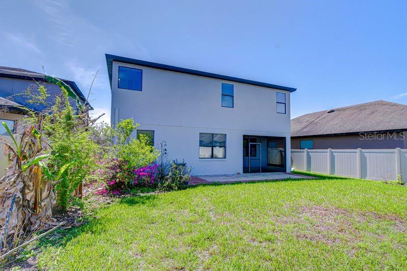 The rear exterior of a two-story house features a small patio and a fenced yard — 871 VINO VERDE CIRCLE, BRANDON, FL