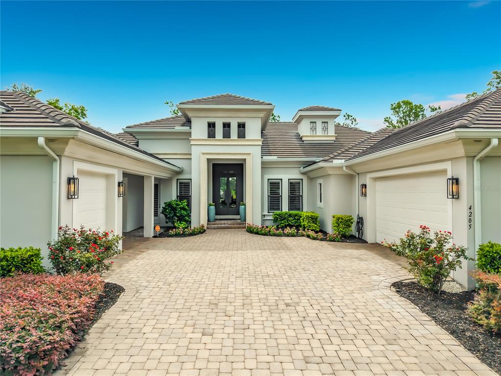 A single-story house with a tiled roof, white stucco exterior, and a paved driveway — 4205 CLARICE ESTATES DRIVE, WINDERMERE, FL
