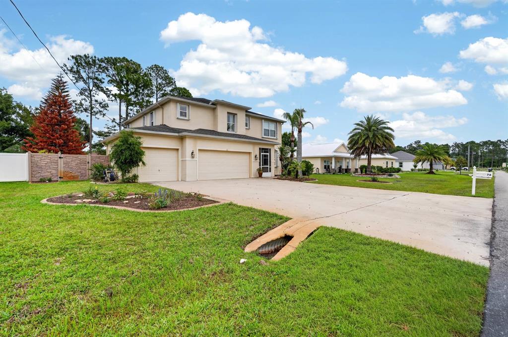 A two-story house with a three-car garage, a concrete driveway, and a landscaped front yard — 76 UNIVERSAL TRAIL, PALM COAST, FL