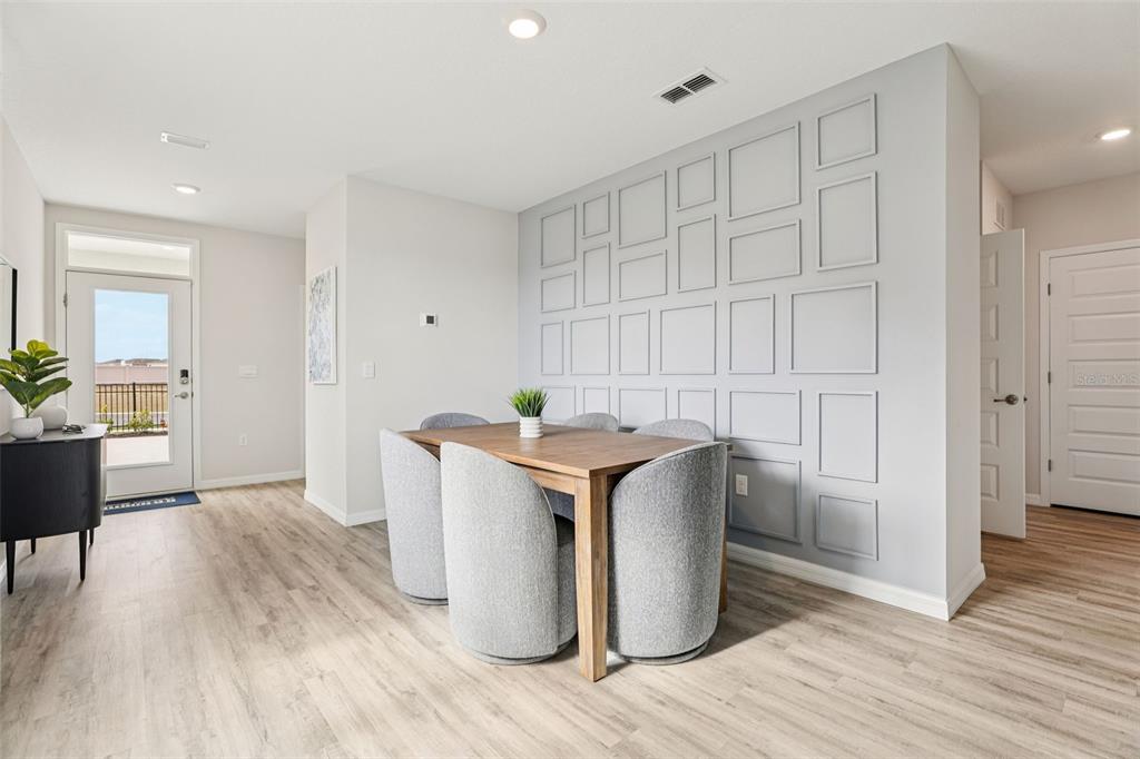 A dining area features a wooden table, gray upholstered chairs, and a paneled accent wall — 4049 GIORGIO DRIVE, WINTER HAVEN, FL