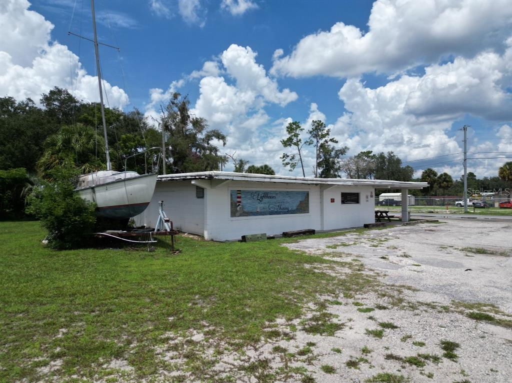 A covered patio features a picnic table, a red door, and a stone-accented wall — 5025 TREIMAN BOULEVARD, DADE CITY, FL