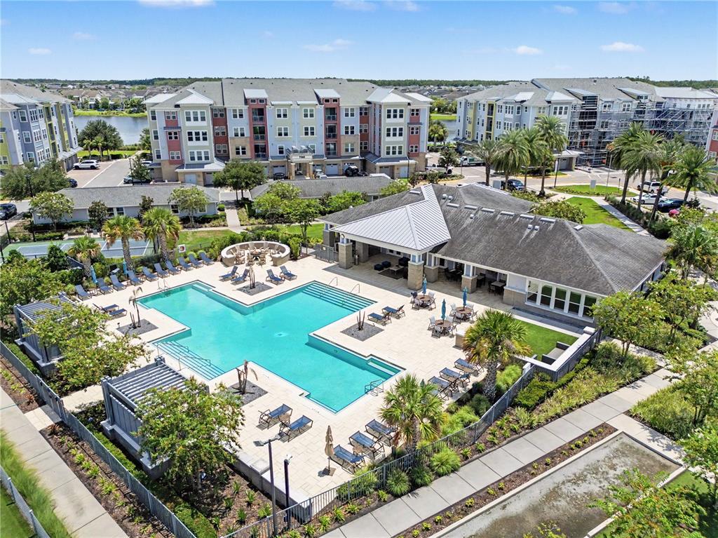 An aerial view shows a swimming pool and clubhouse surrounded by multi-story apartment buildings — 7505 LAUREATE BOULEVARD UNIT 2407, ORLANDO, FL