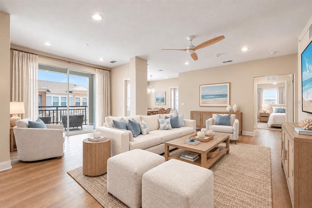 An open-concept living area features light wood-look flooring, recessed lighting, and a sliding glass door — 7505 LAUREATE BOULEVARD UNIT 2407, ORLANDO, FL