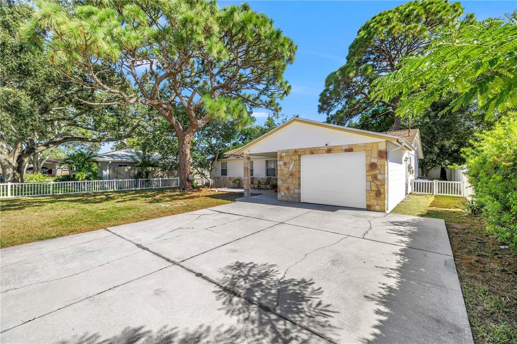 A single-story house with a stone facade, a white garage door, and a concrete driveway — 518 62ND AVENUE NE, ST PETERSBURG, FL