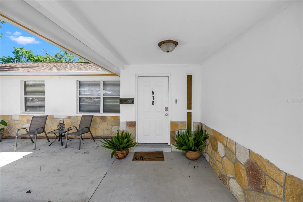 A covered front porch features stone pillars, a white door, and a concrete floor — 518 62ND AVENUE NE, ST PETERSBURG, FL