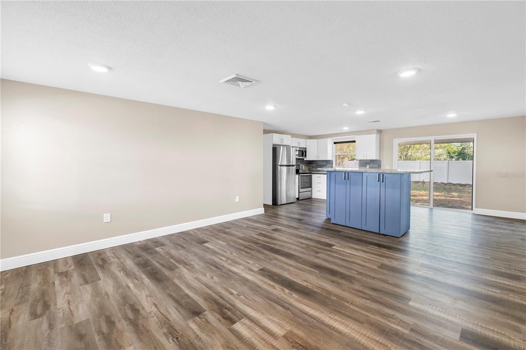A spacious open-concept kitchen and living area with wood-look flooring and a blue island — 518 62ND AVENUE NE, ST PETERSBURG, FL