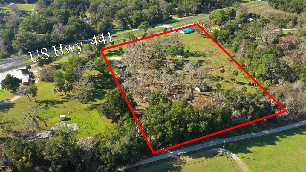 An aerial view shows a wooded lot outlined in red next to a highway — 18585 N HIGHWAY 441, REDDICK, FL
