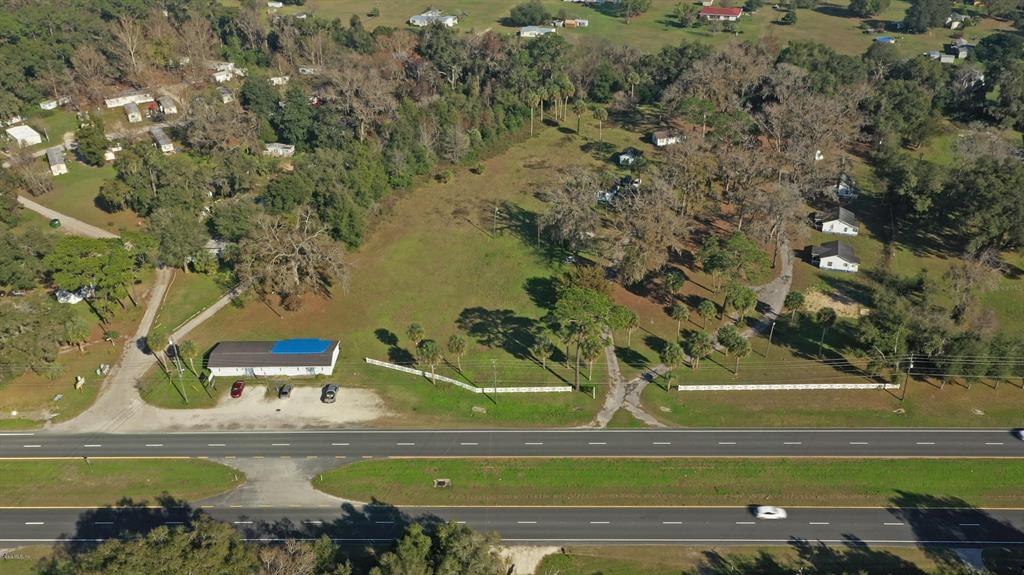 An aerial view shows a large, grassy lot with trees, a building, and a highway — 18585 N HIGHWAY 441, REDDICK, FL