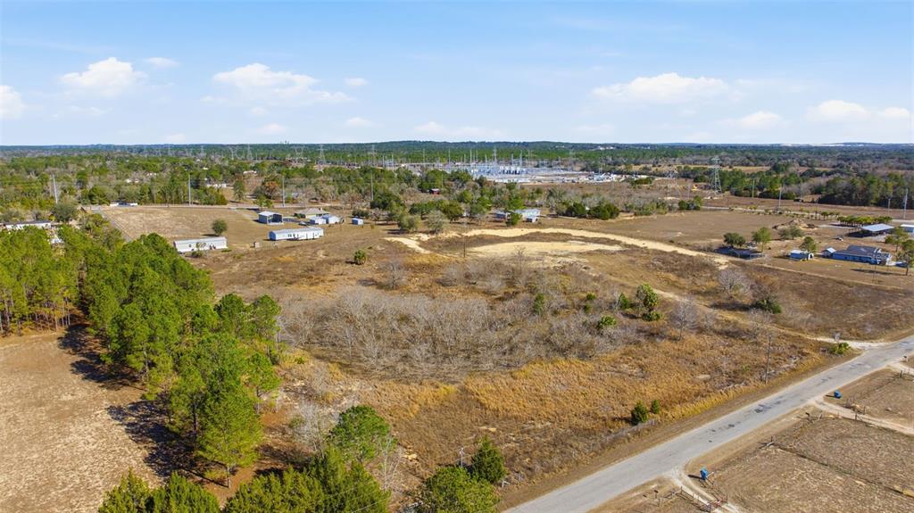 An aerial view of a large, undeveloped rural lot with scattered trees and nearby structures — SWEET GUM ROAD, BROOKSVILLE, FL