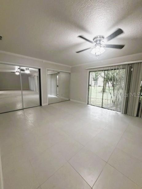 A bedroom with white tile flooring, a ceiling fan, mirrored closet doors, and sliding glass doors — 280 MOREE LOOP UNIT 2, WINTER SPRINGS, FL