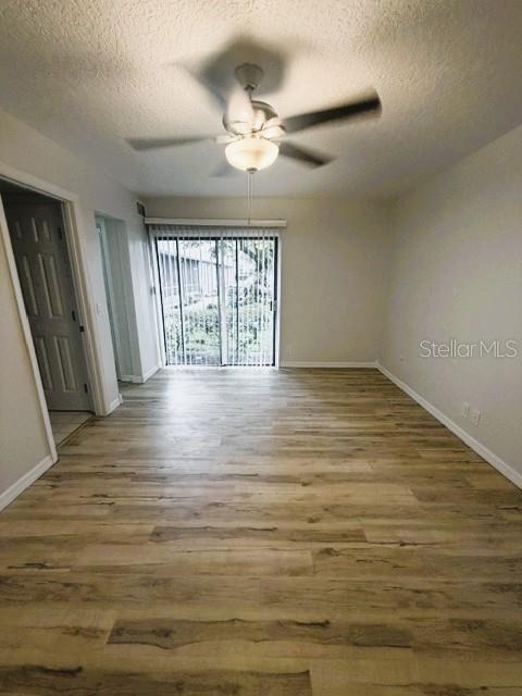 An empty room features wood-look flooring, a ceiling fan, and sliding glass doors — 280 MOREE LOOP UNIT 2, WINTER SPRINGS, FL