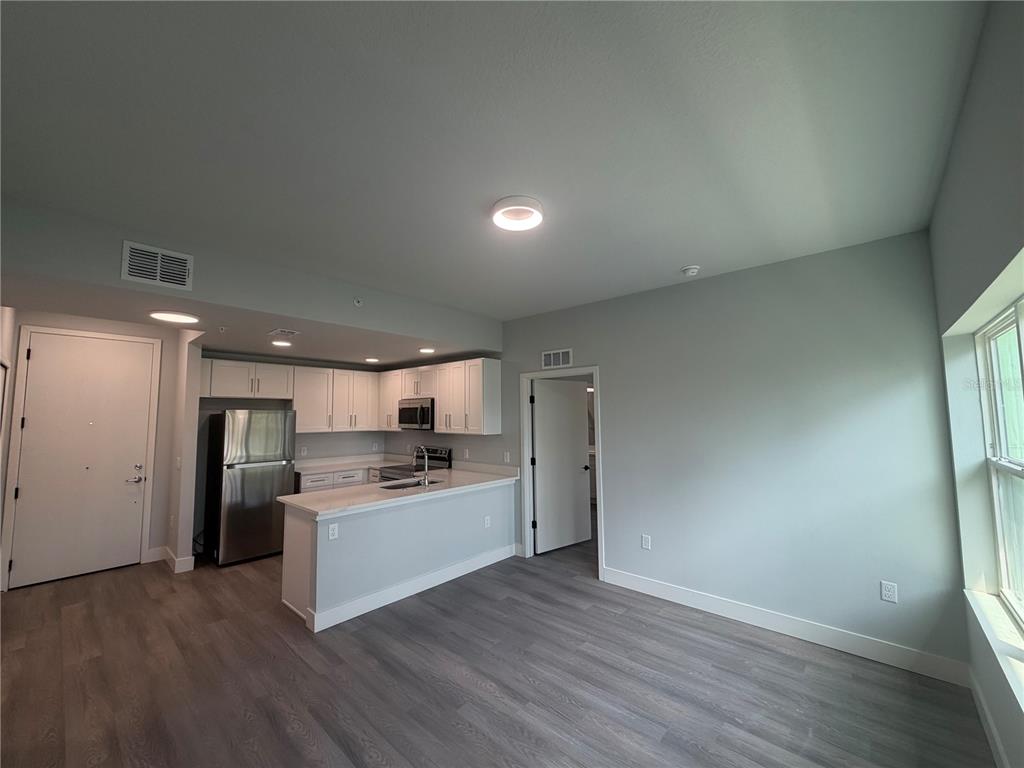 A kitchen with white cabinets and stainless steel appliances opens to a living area — 2240 FLORIDA DRIVE UNIT 203, DELTONA, FL