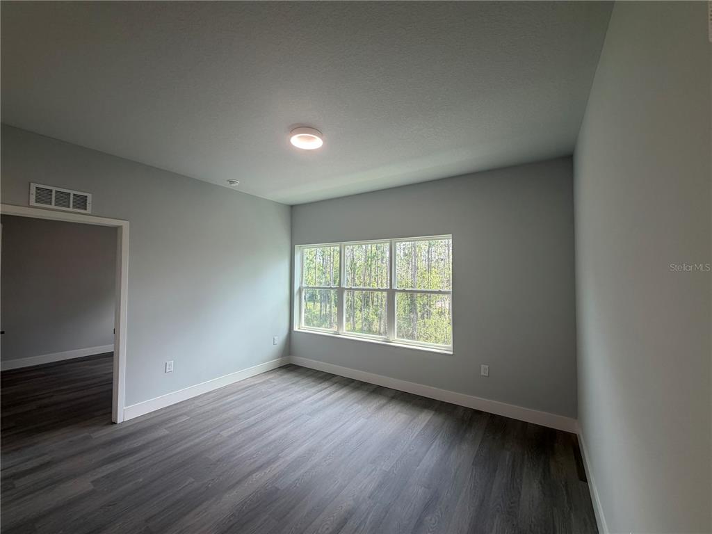 An empty room features light gray walls, dark wood-look flooring, and a large triple window — 2240 FLORIDA DRIVE UNIT 203, DELTONA, FL
