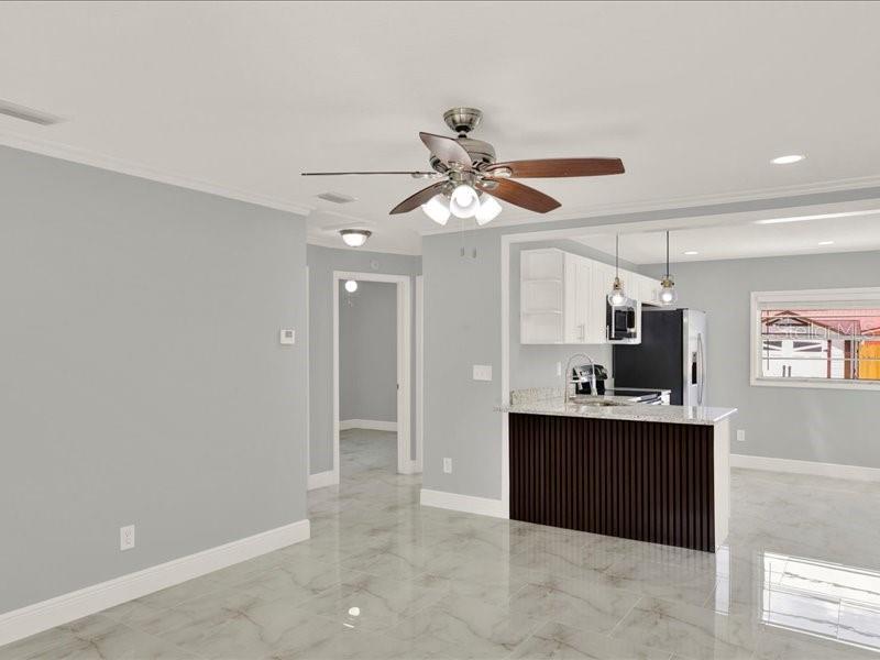 A kitchen with a dark wood island and white cabinets opens into a light-colored living area — 2712 E 99TH AVENUE, TAMPA, FL
