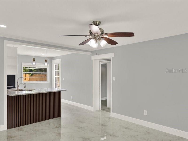 A kitchen with a slatted island and marble-look tile floors opens into a living area — 2712 E 99TH AVENUE, TAMPA, FL