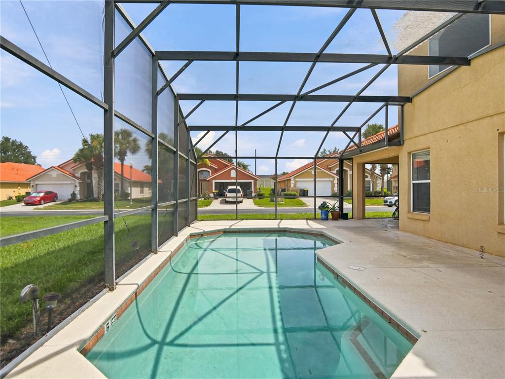 A screened-in swimming pool patio with a concrete deck and views of neighboring houses — 1153 SOLANA CIRCLE, DAVENPORT, FL