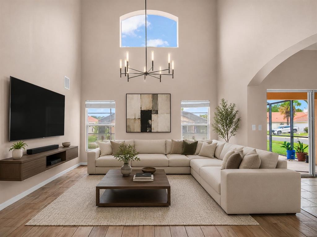 A high-ceilinged living room features a large sectional sofa, a coffee table, and a chandelier — 1153 SOLANA CIRCLE, DAVENPORT, FL