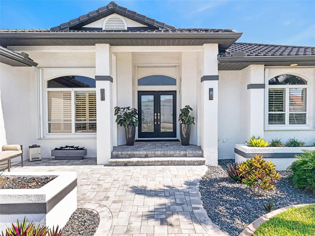 A white house exterior features a double front door, stone steps, and a paved walkway — 1552 AQUI ESTA DRIVE, PUNTA GORDA, FL